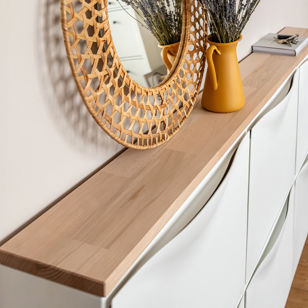 Nahansicht einer Vollholzplatte aus Buche, die auf 3 nebeneinander hängenden IKEA Trones Schränken liegt. Auf der Platte stehen ein Spiegel, eine Kanne mit Trockenblumen, ein Buch und ein Schlüsselbund.