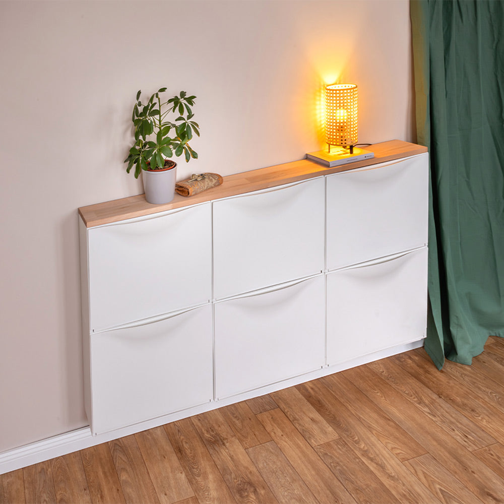 3 weiße IKEA Trones Schuhschränke hängen nebeneinander an der Wand. Auf den Schränken liegt eine passgenaue Vollholzplatte aus Buche. Auf der Platte stehen wiederum diverse Deko-Elemente.
