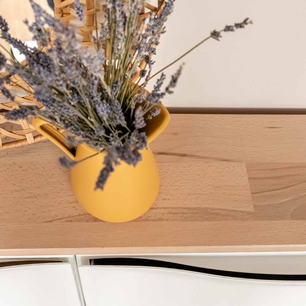 Detailansicht einer geölten Buchenholzplatte, die auf einem IKEA Schuhschrank liegt. Auf der Platte steht eine gelbe Kanne mit getrocknetem Lavendel.