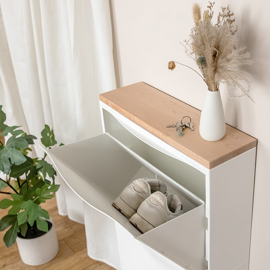 Auf einem weißen IKEA Trones Schuhschrank liegt eine Vollholzplatte aus Buchenholz.