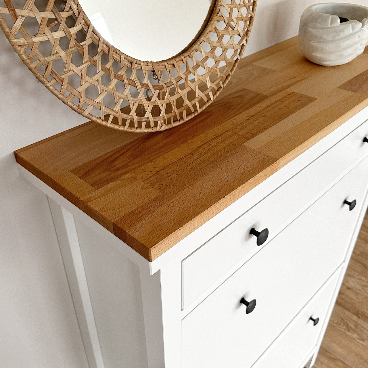 Detailansicht von einer geölten Holzplatte, die auf einem weißen Ikea Hemnes Schuhschrank liegt.