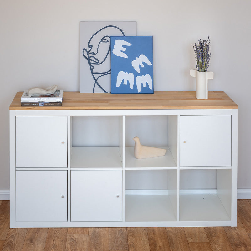 Ein 4 Fach breites Kallax Regal in weiß wurde mit einer Holzplatte aus Vollholz ergänzt.