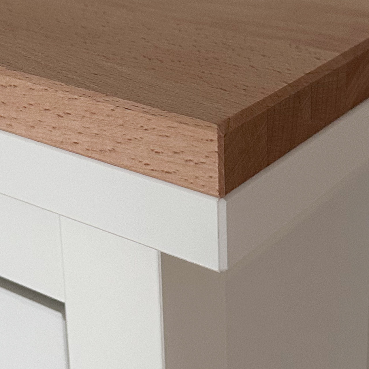 Detailansicht von einer natur belassenen Holzplatte aus Buchenholz, die passgenau auf einem weißen Ikea Hemnes Schuhschrank liegt.